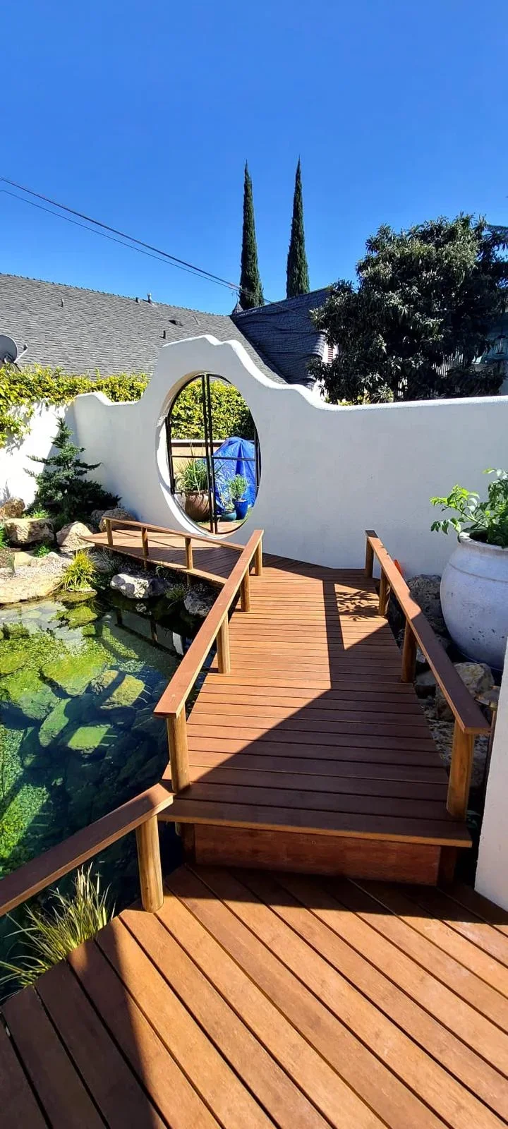 Composite deck with handrails overlooking koi pond and modern white structure