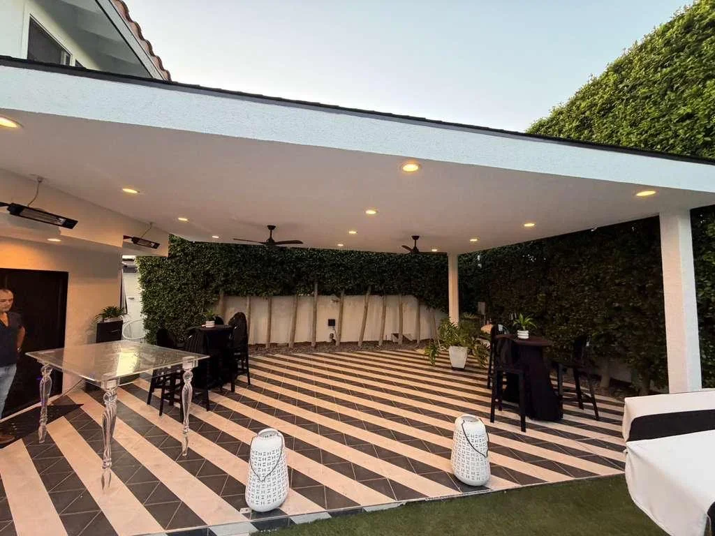 Modern patio with striped pavers, white pergola, recessed lighting, and artificial green walls