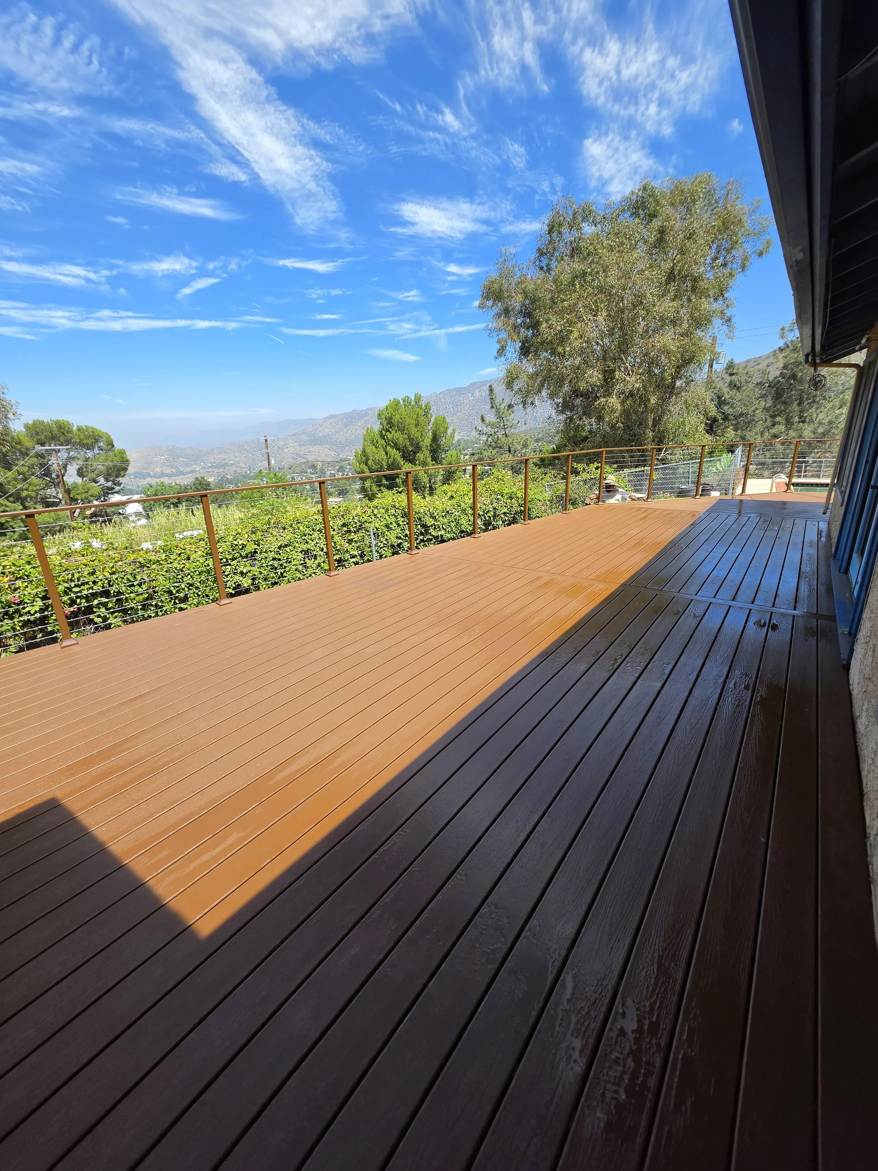 Two-tone composite deck with cable railing overlooking mountain valley landscape