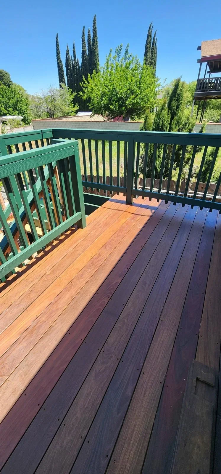 Two-tone composite deck with green railing overlooking landscaped backyard