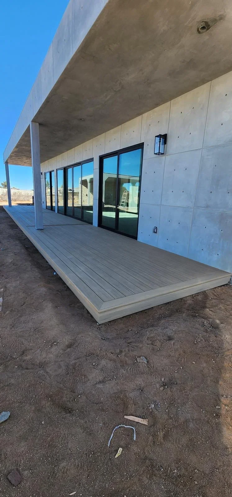 Gray composite deck with black sliding doors and concrete overhang structure