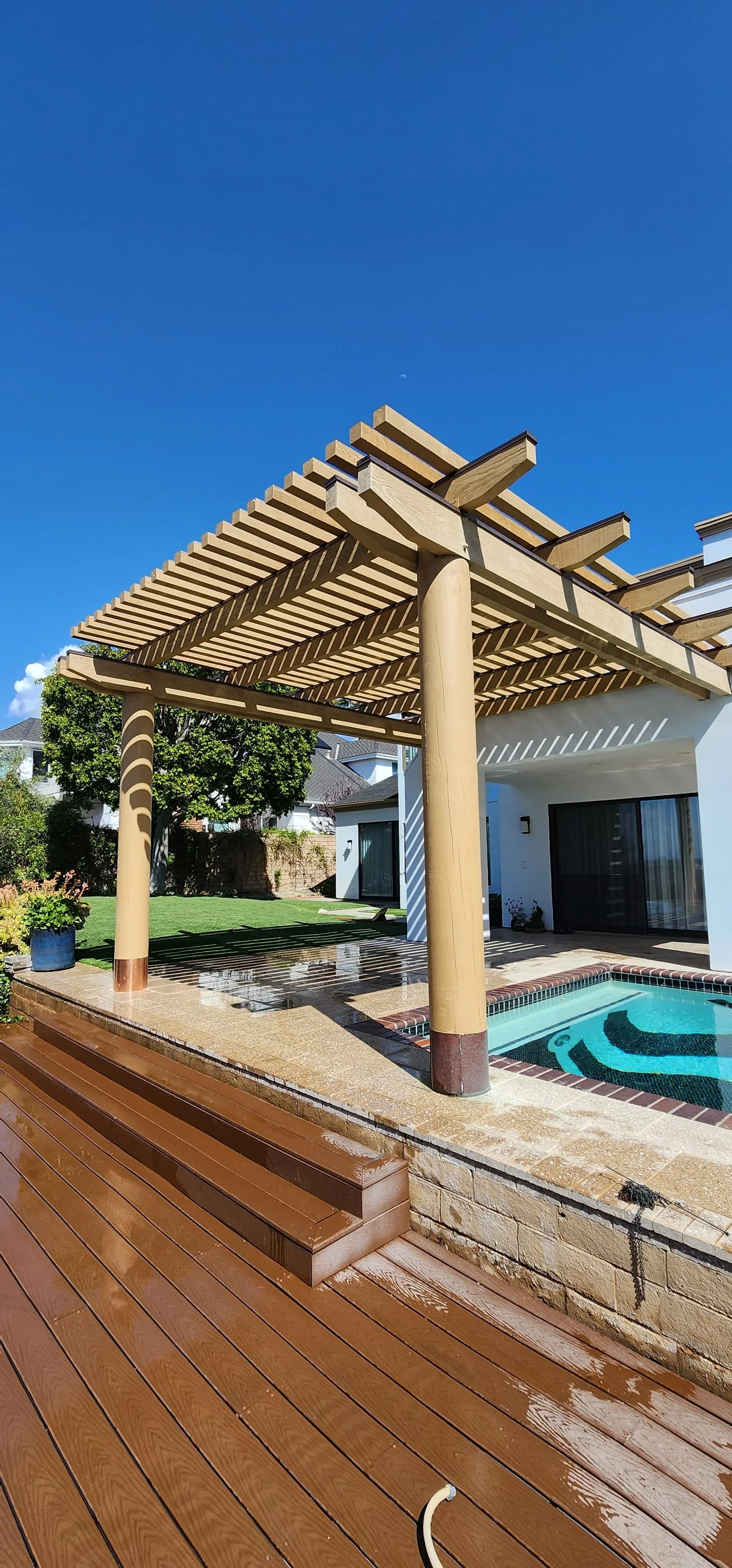 Composite deck with wooden pergola overlooking swimming pool in Cape Coral