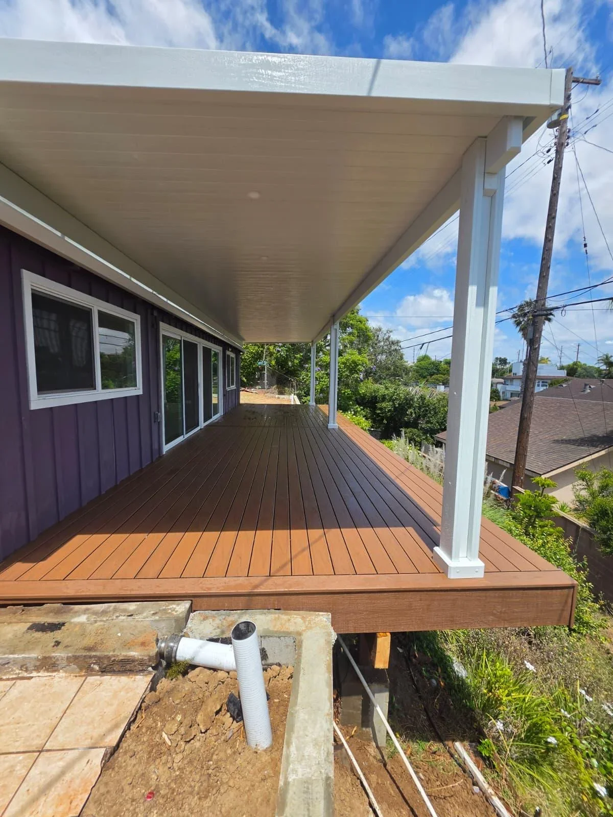 Two-tone composite deck with white aluminum pergola covering residential patio area